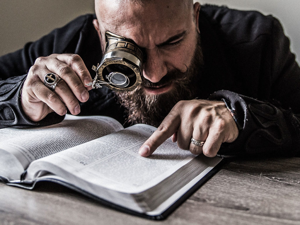 photo of person peering at a book with a magnifying glass