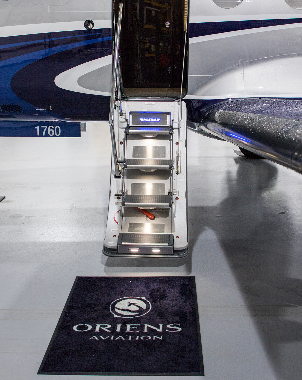 Oriens Aviation logo on a mat in front of the steps of a private plan