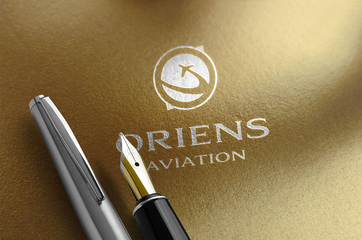 Oriens Aviation logo on gold paper with silver inlay
