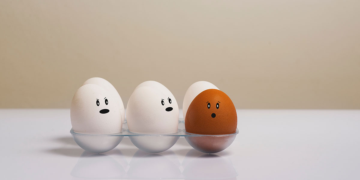 photo of eggs with eyes and mouth with one egg standing out