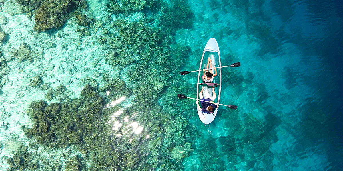 arial photo of a small canoe on the ocean in the Maldives with a man and woman with paddles